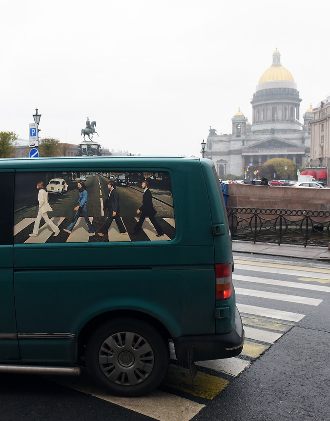 Плакат с группой The Beatles в окне автомобиля, проезжающего по Исаакиевской площади в Санкт-Петербурге